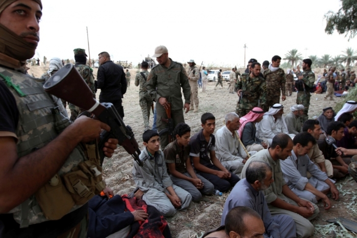 Iraqi families sit after surrendering to Shi'ite fighters and Iraqi Army after they took control of Jurf al-Sakhar from Islamist State militants, October 27, 2014. The families, who were in militant-held areas, surrendered to the army to be transported to safe areas and escape clashes between militants and Iraqi security forces, according to the Iraqi Army and the fighters.