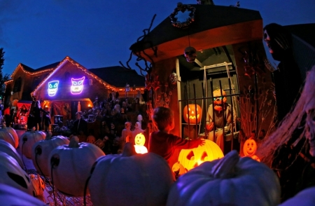 Credit : A visitor to a house covered in Halloween decorations looks over the scene in the front yard in the Chicago suburb of Naperville, Illinois, October 27, 2014. Breathtaking purple-and-orange light displays, zombie graveyards, mutilated mannequins and singin