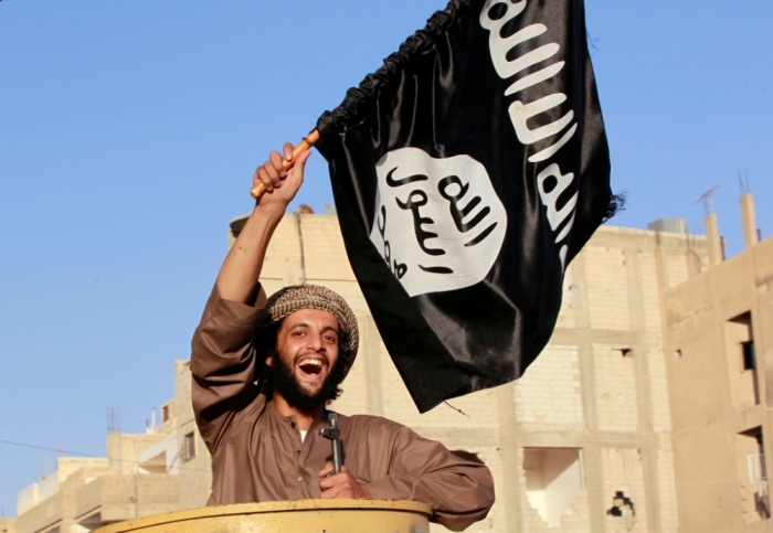 A militant Islamist fighter waving a flag, cheers as he takes part in a military parade along the streets of Syria's northern Raqqa province, June 30, 2014.