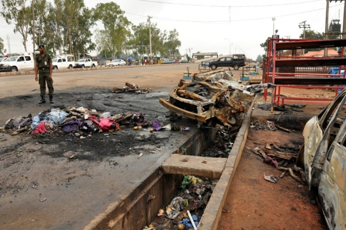 A policeman stands next to the point of impact of a suicide bomb along Alkali Road in Kaduna, Nigeria, July 24, 2014. At least 82 people were killed in two suicide bombings in the north Nigerian city of Kaduna, one aimed at opposition leader and ex-president Muhammadu Buhari and another at a moderate Muslim cleric about to lead a crowd in prayer. Kaduna state governor Mukhtar Yero on Thursday lifted a 24-hour curfew imposed on the state after the bombings.