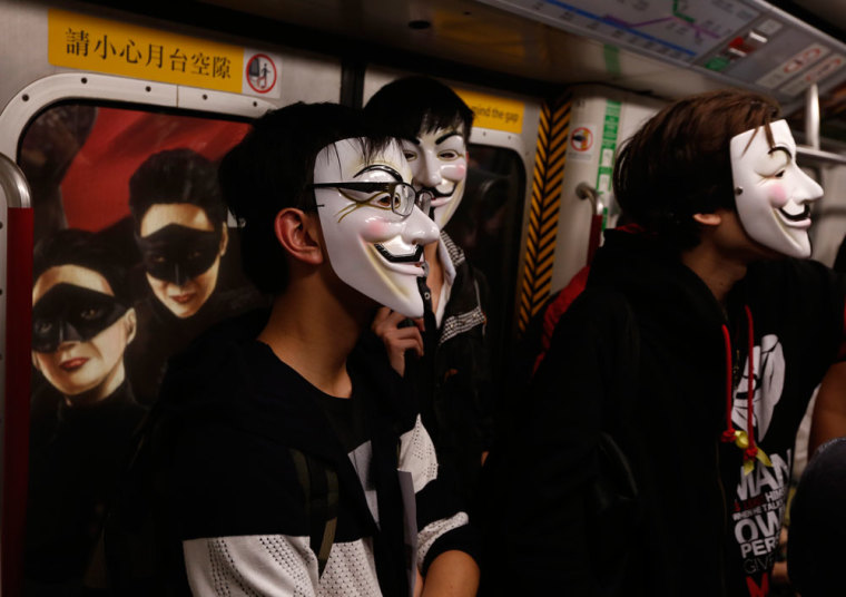 Pro-democracy protesters wearing Guy Fawkes masks stand in front of an advertisement as they take a subway train to a protest site occupied by them as part of the Occupy Central civil disobedience movement in Hong Kong November 5, 2014, the day marking Guy Fawkes Night. Students calling for full democracy for Chinese-ruled Hong Kong are hoping to take their protest to Communist Party rulers in Beijing and are expected to announce details of their new battle plan on Thursday.