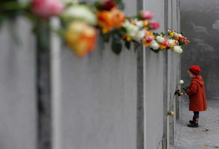 A young girl places a rose at the Berlin Wall memorial in Bernauer Strasse, during a ceremony marking the 25th anniversary of the fall of the Berlin Wall, in Berlin November 9, 2014.