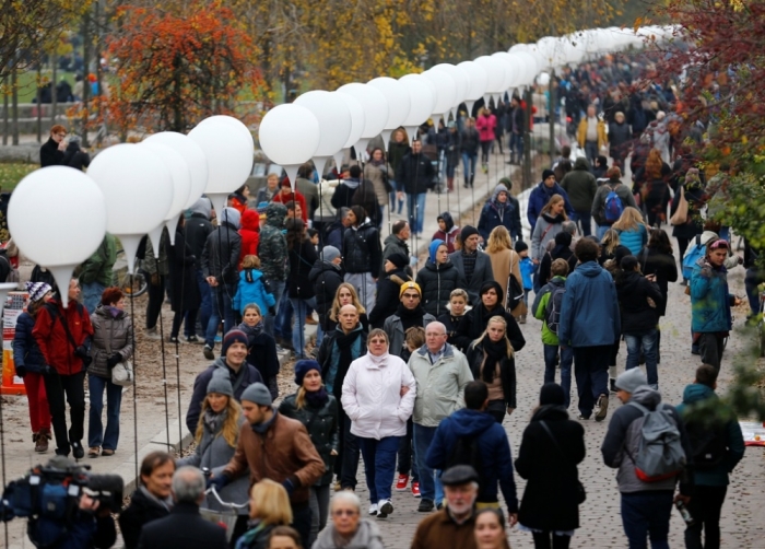 People stroll by the installation 'Lichtgrenze' (Border of Light) along a former Berlin Wall location at Mauer Park in Berlin, November 9, 2014. A part of the inner city of Berlin is being temporarily divided from November 7 to 9, with a light installation featuring 8000 luminous white balloons, following the 9.5-mile (15.3 kmilometre) path the Berlin Wall once occupied, to commemorate the 25th anniversary of the fall of the Wall.