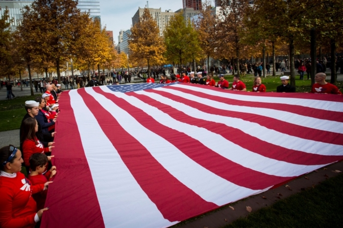 People unfurl an American Flag at the 9/11 Memorial in New York, November 9, 2014. The flag ceremony was part of the 9/11 Memorial's Salute to Service, a five day tribute to veterans for Veterans Day.