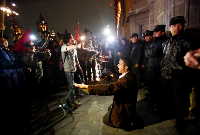 A member of security kneels on the ground trying to calm protesters outside Mexican President Enrique Pena Nieto's ceremonial palace during a protest denouncing the apparent massacre of 43 trainee teachers, in the historic center of Mexico City, late November 8, 2014.