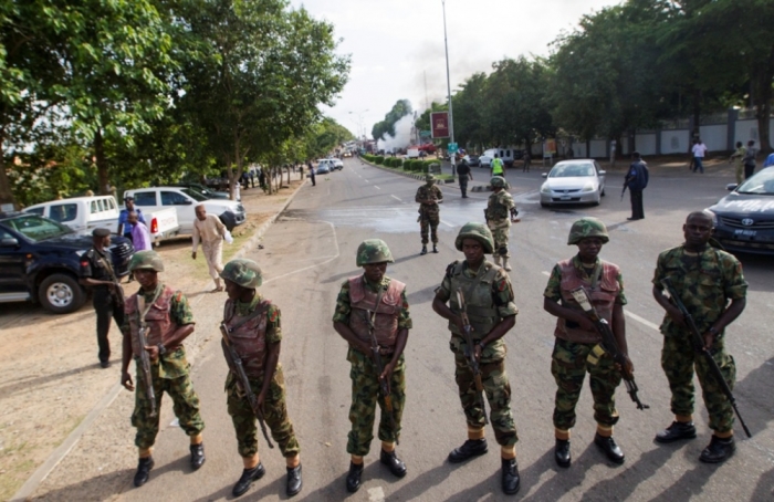Nigerian army soldiers stand guard as they cordon off a road leading to the scene of a blast at a business district in Abuja June 25, 2014. At least 21 people were killed when a suspected bomb tore through the crowded shopping district in the Nigerian capital Abuja during rush hour on Wednesday, police said, adding to the toll of thousands killed in attacks this year.
