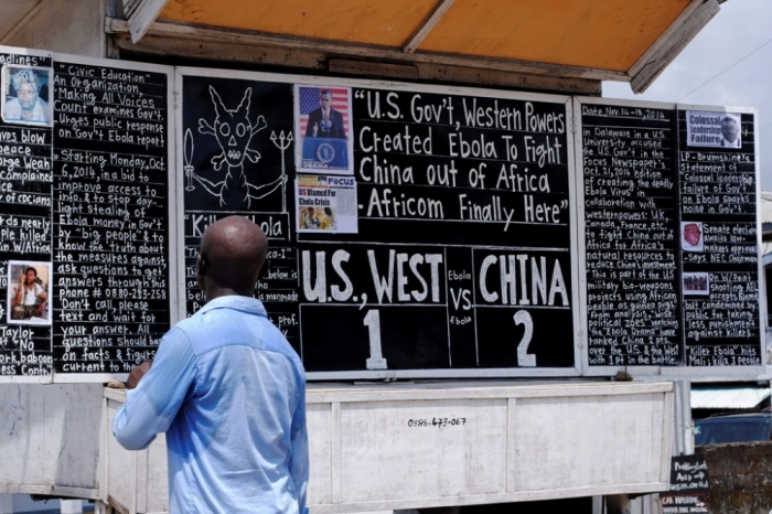 A man reads a board extolling China's contribution to the fight against Ebola, along a road in Monrovia, November 15, 2014. China is dispatching health experts and medical staff to Liberia and Sierra Leone in response to U.N. calls for a greater global effort to fight the deadly Ebola virus in West Africa.