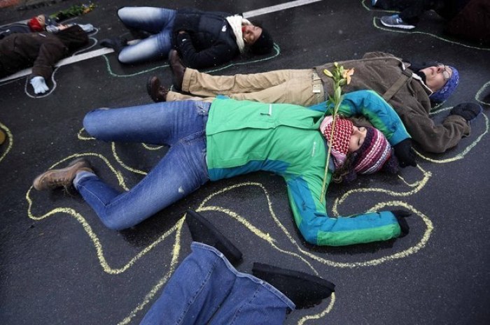 A demonstrator sprinkles flowers over people laying on the ground with chalk outlines to represent a mock crime scene during a protest marking the 100th day since the shooting death of Michael Brown, St. Louis, Missouri, November 16, 2014.
