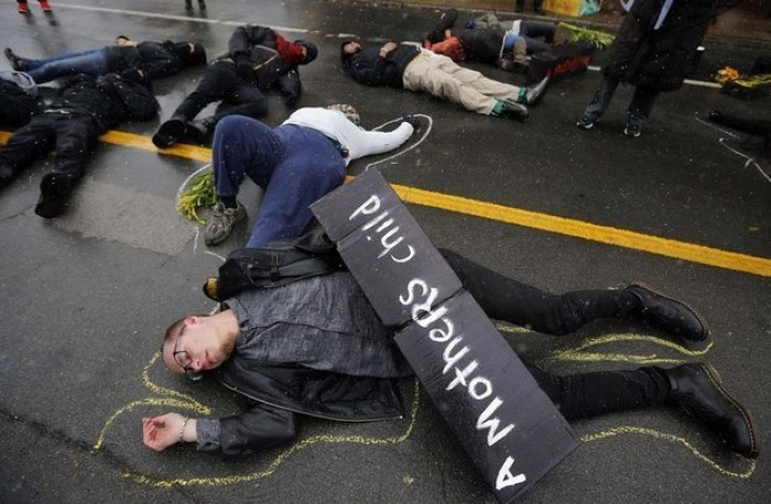 Demonstrators lay on the ground with chalk outlines to represent a mock crime scene during a protest marking the 100th day since the shooting death of Michael Brown in St. Louis, Missouri November 16, 2014.