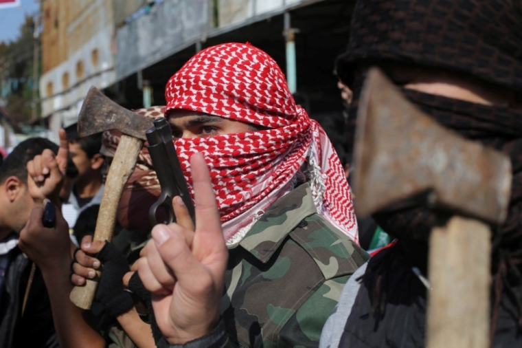 Masked Palestinians hold axes and a gun as they celebrate with others an attack on a Jerusalem synagogue, in Rafah in the southern Gaza Strip, November 18, 2014. Two Palestinians armed with a meat cleaver and a gun killed four people in a Jerusalem synagogue on Tuesday before being shot dead by police, the deadliest such incident in six years in the holy city amid a surge in religious conflict.