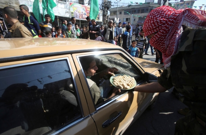 A masked Palestinian distributes sweets as he celebrates with others an attack on a Jerusalem synagogue, in Rafah in the southern Gaza Strip, November 18, 2014. Two Palestinians armed with a meat cleaver and a gun killed four people in a Jerusalem synagogue on Tuesday before being shot dead by police, the deadliest such incident in six years in the holy city amid a surge in religious conflict.