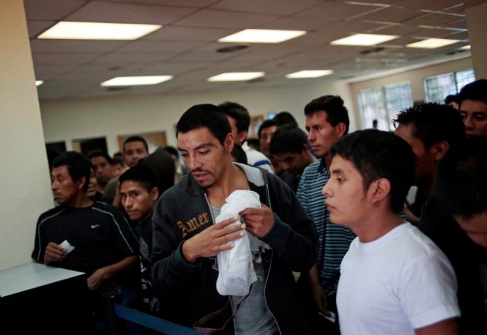 Illegal immigrants from Guatemala, who were deported from the U.S., wait while collecting their belongings from immigration officers processing their re-entry at La Aurora airport in Guatemala City, August 14, 2014. A flight carrying 135 illegal Guatemalan migrants which departed from Brownfield, Texas, U.S., arrived at La Aurora airport on Tuesday, according to immigration authorities.