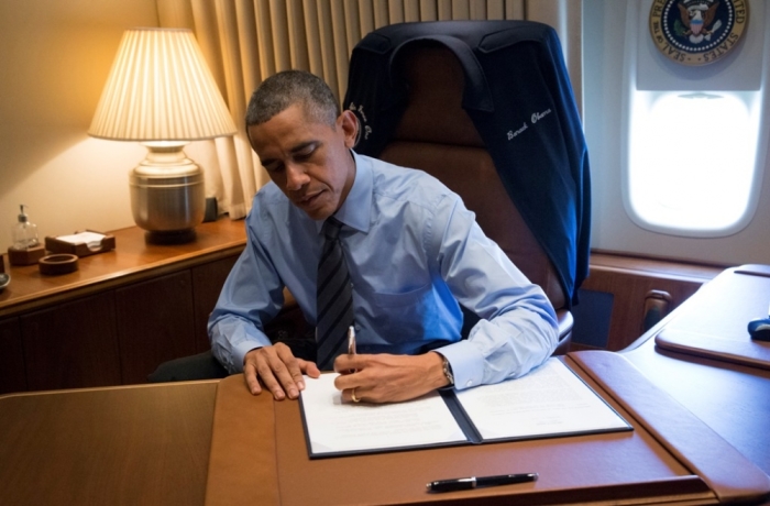 U.S. President Barack Obama signs two presidential memoranda associated with his executive actions on immigration from his office on Air Force One upon his arrival in Las Vegas, Nevada, November 21, 2014. Obama imposed the most sweeping immigration reform in a generation on Thursday, easing the threat of deportation for about 5 million illegal immigrants.