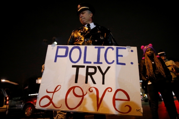 A man holds a sign outside the Ferguson Police Department in Ferguson, Missouri, November 24, 2014. A Missouri grand jury has made a decision on whether to indict a white police officer in the fatal shooting of an unarmed black teenager in Ferguson, a killing that sparked angry protests in the St. Louis suburb, the Washington Post reported on Monday.