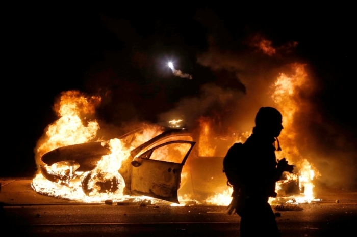 A police car burns on the street after a grand jury returned no indictment in the shooting of Michael Brown in Ferguson, Missouri, November 24, 2014. Gunshots were heard and bottles were thrown as anger rippled through a crowd outside the Ferguson Police Department in suburban St. Louis after authorities on Monday announced that a grand jury voted not to indict a white officer in the August shooting death of an unarmed black teen.