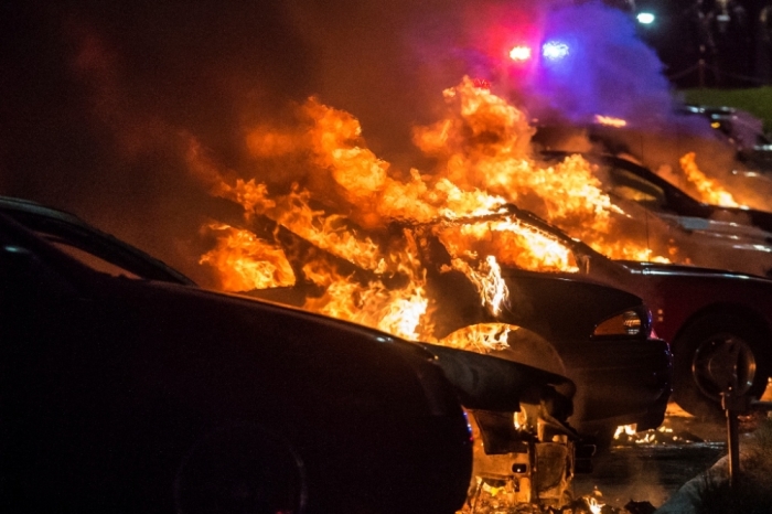 Vehicles at a car dealership are set afire in Ferguson, Missouri, early morning November 25, 2014. Gunshots rang out and buildings burned in a Midwestern suburb after a grand jury decided on Monday not to indict a white police officer over the fatal August shooting of an unarmed black teenager, sparking a fresh wave of racially tinged violence. At least a dozen buildings were set on fire in Ferguson, Missouri, most of them left destroyed.
