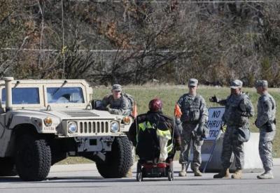A man in a wheelchair speaks to the National Guard as they stand by a humvee stationed across a mall in Ferguson, Missouri, November 25, 2014.