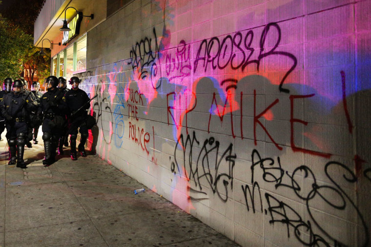 Police officers shadows are cast onto graffiti on the wall of a Subway during the second night of demonstrations in Oakland, California, following the grand jury decision in the shooting of Michael Brown in Ferguson, Missouri, November 25, 2014