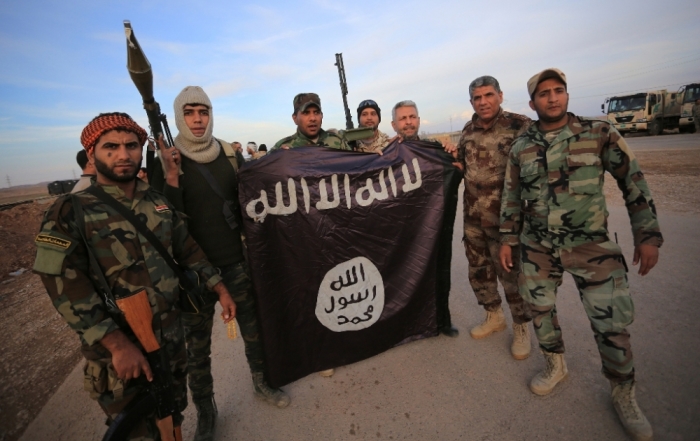 Iraqi Shiite fighters pose with an Islamic State flag which they pulled down on the front line in Jalawla, Diyala province, Iraq, November 23, 2014.