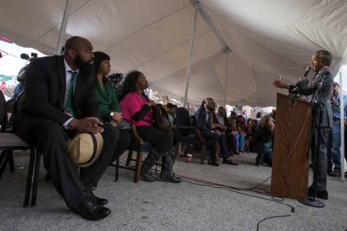 Michael Brown Sr. (L), the father of 18-year-old Michael Brown, watches veteran civil rights activist Rev. Al Sharpton speak under a makeshift tent next to the Flood Christian Church during Sunday service in Ferguson, Missouri, November 30, 2014. The Flood Christian Church was burnt during recent unrest in Ferguson. Sharpton preached on Sunday to a congregation of some 2,500 worshippers at the St. Louis church where Michael Brown's funeral was held in August. The dead teen's parents were among the congregation.
