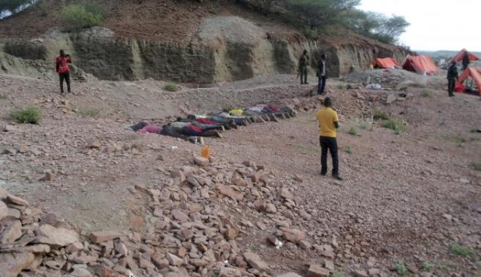 People stand near bodies lined up on the ground at a quarry site where attackers killed at least 36 workers in a village in Korome, outside the border town of Mandera December 2, 2014.