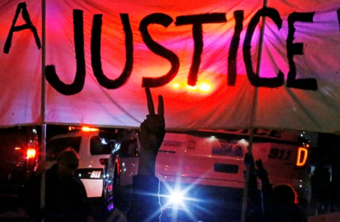 A protester holds up a peace sign during a demonstration over the shooting death of Michael Brown in Webster Grove, Missouri, December 2, 2014. Police officer Darren Wilson fatally shot Brown during an Aug. 9 physical confrontation in which Brown, at one point, allegedly grabbed the officer's gun in Ferguson, Missouri, about 12 miles outside St. Louis, which set off a national debate on race and policing.