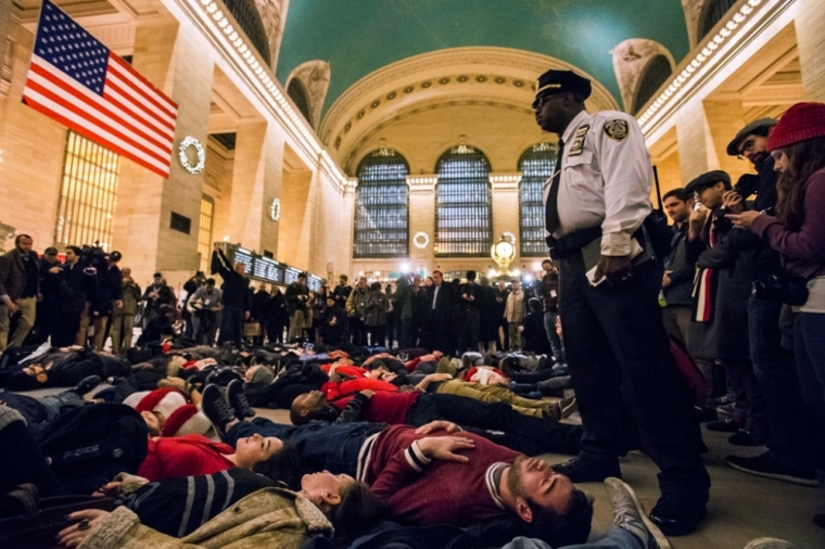 A police officer stands over activists, demanding justice for the death of Eric Garner, as they stage a 'die-in' during rush hour at Grand Central Terminal in the Manhattan borough of New York, December 3, 2014. A New York City grand jury on Wednesday returned no indictment against a white police officer who used a chokehold on an unarmed black man who died as police tried to arrest him for illegally selling cigarettes, local media reported. The grand jury in the city's borough of Staten Island decided against criminal charges for New York police officer Daniel Pantaleo in the death of Eric Garner. The deadly encounter on July 17 was captured on a video that quickly spread over the Internet and helped fuel debates about how U.S. police use force, particularly against minorities.