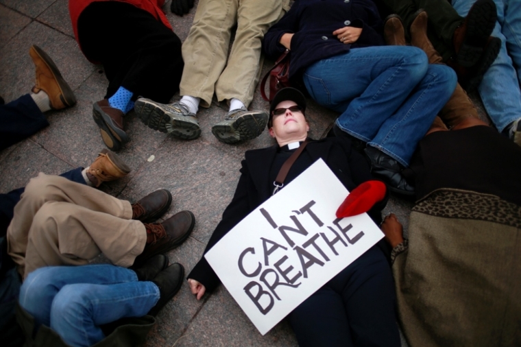 A protester, demanding justice for Eric Garner, holds a placard while staging a 'die-in' with dozens of others in downtown White Plains, New York, December 5, 2014.