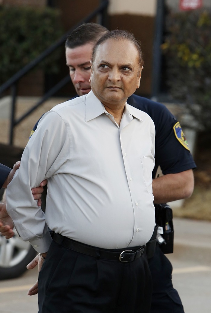Nareshkumar Patel, 62, is led away in handcuffs by Warr Acres police officers at his clinic, Outpatient Services for Women, in Warr Acres, Oklahoma, Tuesday, December 9, 2014.
