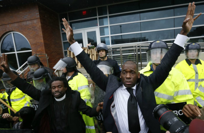 The Rev. Osagyefo Sekou (L) and Pastor Jamal H. Bryant hold up their hands as the riot police move in during a protest on Oct. 13, 2014, at the Ferguson Police Department in Ferguson, Missouri.