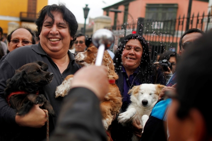 People react as their pets are blessed by a Catholic priest during a ceremony to commemorate the feast of Saint Francis of Assisi, outside the Saint Francis church in Lima, Peru, October 12, 2014. Saint Francis is the patron saint of animals and the environment.