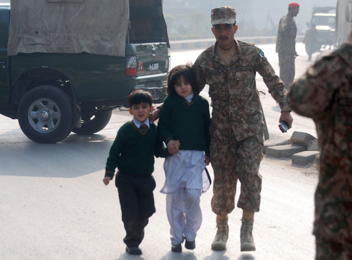 A soldier escorts schoolchildren from the Army Public School that is under attack by Taliban gunmen in Peshawar, December 16, 2014. Taliban gunmen in Pakistan took hundreds of students and teachers hostage on Tuesday in a school in the northwestern city of Peshawar, military officials said