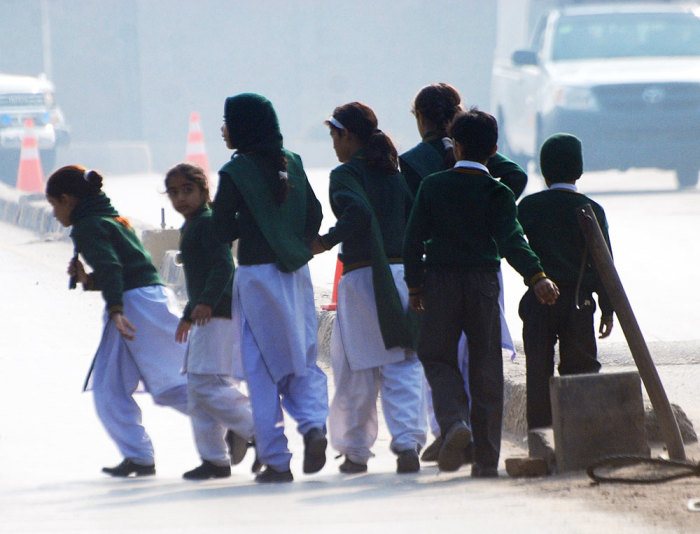 Schoolchildren cross a road as they move away from a military run school that is under attack by Taliban gunmen in Peshawar, December 16, 2014. Taliban gunmen in Pakistan took hundreds of students and teachers hostage on Tuesday in a school in the northwestern city of Peshawar, military officials said.
