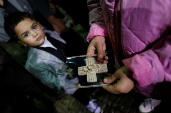 An Iraqi Christian refugee girl holds a souvenir of the Holy Family as a boy looks on at a church in Hazmiyeh, near Beirut, Lebanon, December 12, 2014. Christian leaders led the service for around 600 Iraqi Christian refugees, many of them children and the elderly. Iraqi Christians who sought refuge in Lebanon after Islamist militants tore through their homeland said they had no idea when they would be able to return as they gathered for prayers ahead of Christmas.