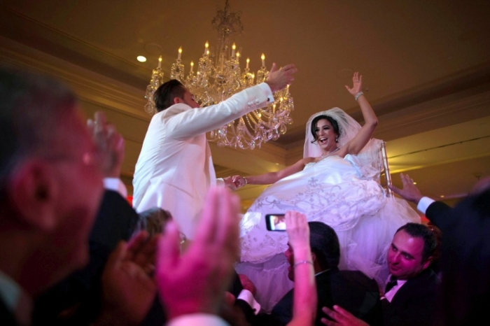 Megan Moshar (R), 26, who is of Persian, German and Filipino descent, dances with her husband George Safar, 27, whose parents are from Syria, as they are both lifted into the air during their wedding reception in Pasadena, California August 16, 2014. Los Angeles is a culturally thriving city and one of the most ethnically diverse in the United States, with a population that is 48.5 percent Latino and 11.3 percent Asian, according to a 2010 census. Immigration has become a hot button issue ahead of U.S. midterm elections on November 4, and despite arguments from the White House that legal migration benefits businesses, a recent opinion poll found most Americans believe migrants place a burden on the economy.