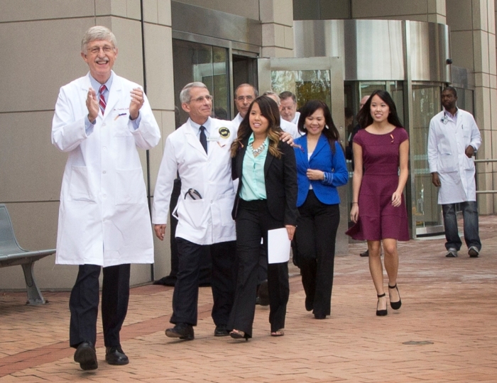 NIH Director Dr. Francis Collins, (L), NIAID Director Dr. Anthony Fauci (2nd L) and NIH Clinical Center Director Dr. John Gallin (3rd L, rear) exit the NIH Clinical Center in Bethesda, Maryland, with recently discharged Ebola patient Nina Pham in this October 24, 2014, handout photo. Pham, who contracted the disease while treating a man who later died of Ebola in a Dallas hospital, had been undergoing treatment at the National Institutes of Health in Bethesda, Maryland, since October 16.