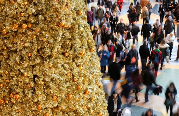 People walk in a shopping mall next a Christmas tree in Berlin, Germany, December 19, 2014.