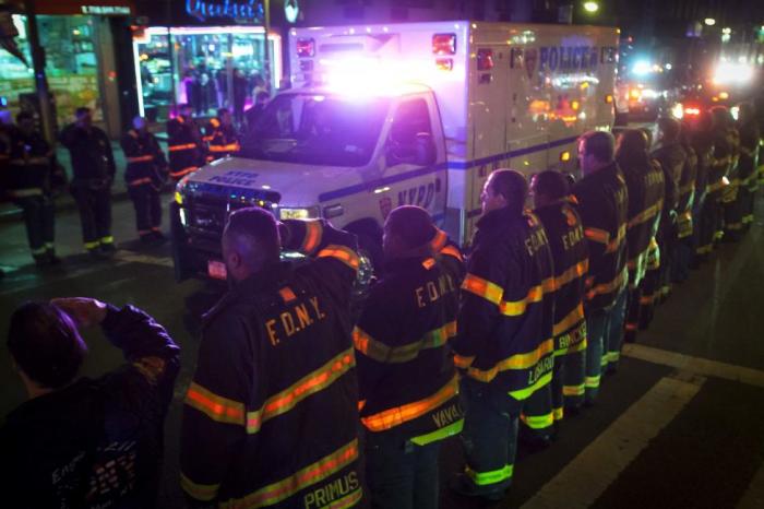 An ambulance carrying one of the two New York Police officers who were shot dead passes by a New York Fire Department honor guard along Broadway in the Brooklyn borough of New York, December 20, 2014.