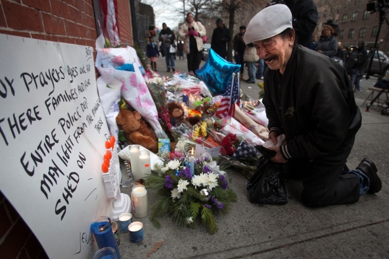 Ernesto Miranda kneels and weeps at a makeshift memorial at the site where two police officers were shot in the head in the Brooklyn borough of New York, December 21, 2014. Miranda was a long time friend of officer Rafael Ramos. The NYPD officers, Wenjian Liu and Rafael Ramos were shot and killed as they sat in a marked squad car in Brooklyn on Saturday afternoon, New York Police Commissioner William Bratton said. The suspect in the shooting then shot and killed himself, Bratton said at a news conference at the Brooklyn hospital where the two officers were taken.