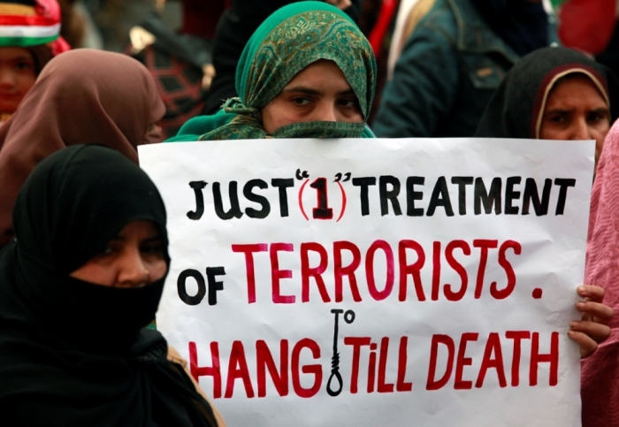 A supporter of political party Pakistan Awami Tehreek, holds a sign with others to condemn the attack by Taliban gunmen on the Army Public School in Peshawar, during a rally in Lahore, December 21, 2014. Taliban gunmen broke into the school and opened fire on Tuesday, killing 132 students and nine staff members, witnesses said, in the bloodiest massacre the country has seen for years.