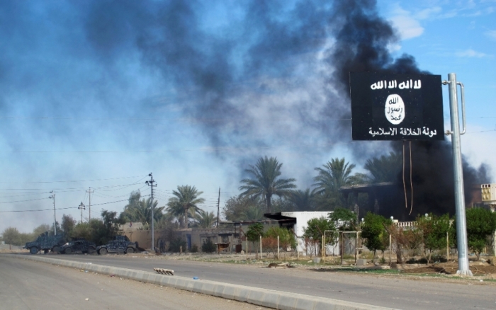 Smoke raises behind an Islamic State flag after Iraqi security forces and Shiite fighters took control of Saadiya in Diyala province from Islamist State militants, November 24, 2014. Iraqi forces said on Sunday they retook two towns north of Baghdad from Islamic State fighters, driving them from strongholds they had held for months and clearing a main road from the capital to Iran. There was no independent confirmation that the army, Shiite militia and Kurdish peshmerga forces had completely retaken Jalawla and Saadiya, about 115 km (70 miles) northeast of Baghdad. Many residents fled the violence long ago. At least 23 peshmerga and militia fighters were killed and dozens were wounded in Sunday's fighting, medical and army sources said.