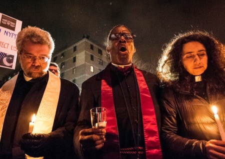 Mourners take part in a prayer vigil at the site where two New York Police Department (NYPD) officers were fatally shot in the Brooklyn borough of New York December 21, 2014. New York Mayor Bill de Blasio faced the biggest crisis of his time in office on Sunday following the fatal shooting of two police officers, in an attack intended as retribution for recent U.S. police killings of unarmed black men. Police said the daylight Saturday shooting was the work of a 28-year-old black man who traveled from Baltimore that day after shooting and wounding his girlfriend, having warned on social media that he planned to be "putting wings on pigs," using an anti-police slur.