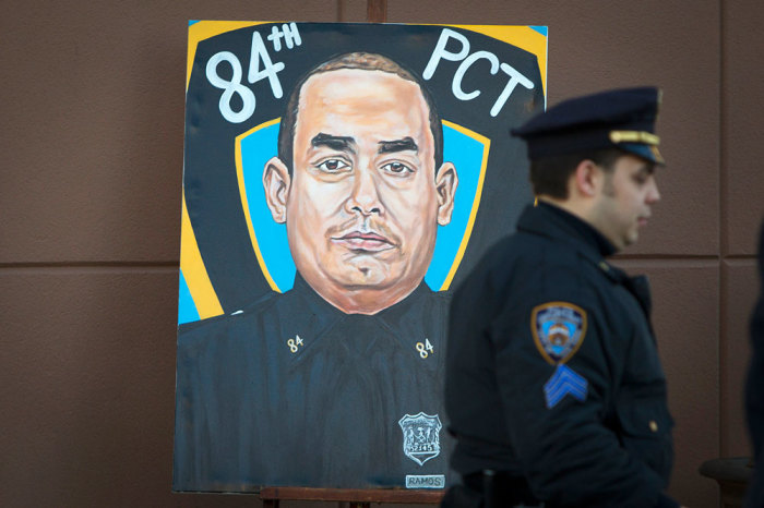 A police officer walks past a painting of NYPD officer Rafael Ramos in his funeral at Christ Tabernacle Church in the Queens borough of New York December 27, 2014. Thousands of police and other mourners were expected to fill a New York City church and surrounding streets for the funeral Saturday of one of two police officers ambushed by a gunman who said he was avenging the killing of unarmed black men by police.