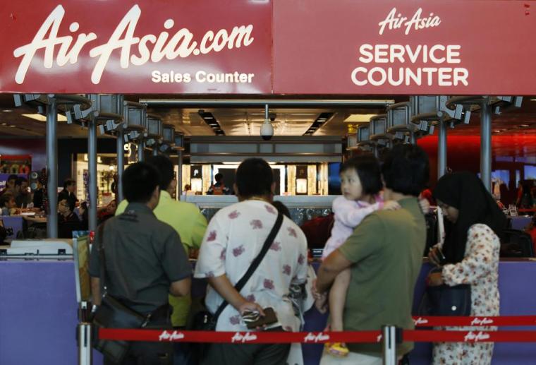People queue at an AirAsia counter at Changi Airport in Singapore December 28, 2014.