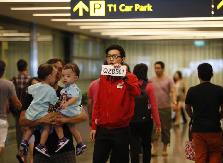 A Changi Airport staff holds up a sign to direct possible next-of-kins of passengers of AirAsia flight QZ 8501 from Indonesian city of Surabaya to Singapore, at Changi Airport in Singapore December 28, 2014.