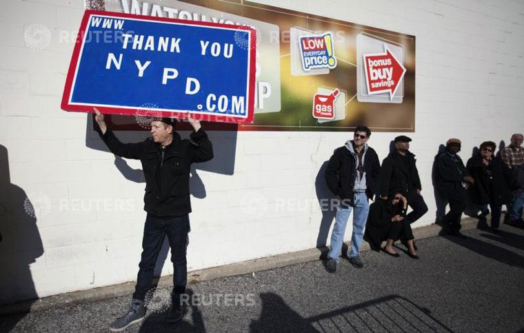 A man carries a sign near the Christ Tabernacle Church during the funeral service for slain New York Police Department (NYPD) officer Rafael Ramos in the Queens borough of New York December 27, 2014. Targeted for their uniform, Rafael Ramos and Wenjian Liu were slain last Saturday afternoon while sitting in their patrol car in Brooklyn in what is only the seventh instance of police partners being killed together in the city in more than 40 years. Thousands of police officers from departments around the country, including those in St. Louis, Atlanta, Boston, New Orleans and Washington, D.C., were expected to join U.S. Vice President Joe Biden and other officials for the funeral service at the church on Saturday.