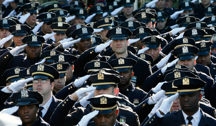 Police salute outside the Christ Tabernacle Church as the casket of slain New York Police Department (NYPD) officer Rafael Ramos is carried from the church following his funeral service in the Queens borough of New York December 27, 2014. Targeted for their uniform, Ramos and Wenjian Liu were slain last Saturday afternoon while sitting in their patrol car in Brooklyn in what is only the seventh instance of police partners being killed together in the city in more than 40 years. Thousands of police officers from departments around the country, including those in St. Louis, Atlanta, Boston, New Orleans and Washington, D.C., were expected to join U.S. Vice President Joe Biden and other officials for the funeral service at the church on Saturday.