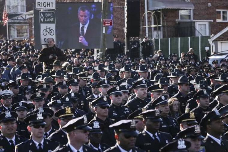 Law enforcement officers turn their backs on a live video monitor showing New York City Mayor Bill de Blasio as he speaks at the funeral of slain New York Police Department officer Rafael Ramos near Christ Tabernacle Church in the Queens borough of New York, December 27, 2014.