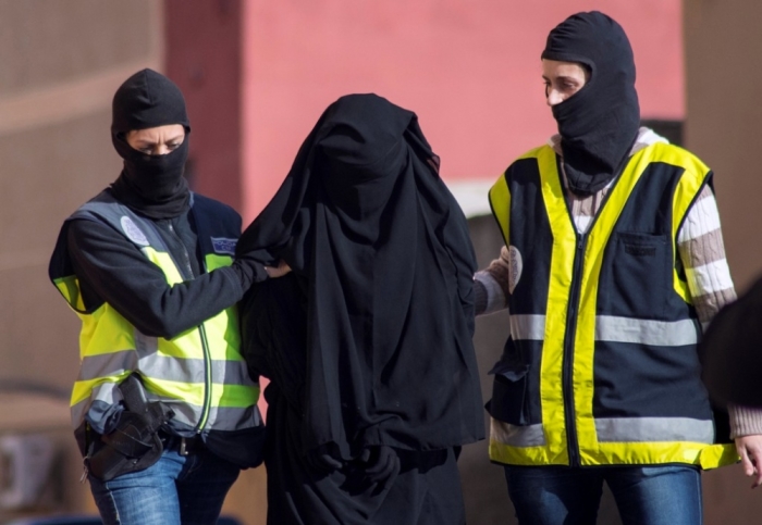 Masked Spanish police officers lead a detained woman in Melilla, December 16, 2014. Spanish and Moroccan police have arrested seven people in a ongoing joint swoop on suspected efforts to recruit women to go to Syria and Iraq to support Islamic State insurgents, the Spanish Interior Ministry said on Tuesday.