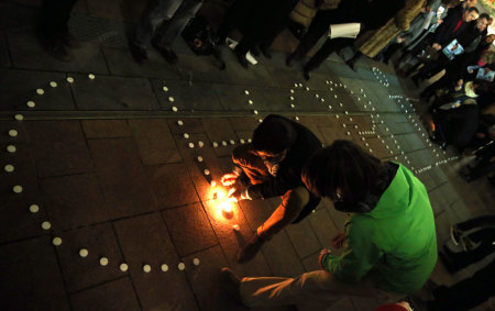 People try to light candles to form the word "Charlie" to pay tribute to the victims of a shooting by gunmen at the offices of weekly satirical magazine Charlie Hebdo in Paris, in front of the European Parliament in Brussels January 7, 2015. Gunmen stormed the Paris offices of the weekly satirical magazine Charlie Hebdo, renowned for lampooning radical Islam, killing at least 12 people, including two police officers in the worst militant attack on French soil in recent decades